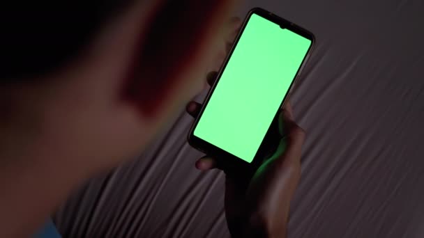 Man in Dark on Bed Holds e Exemplos Smartphone com tela sensível ao toque verde. — Vídeo de Stock