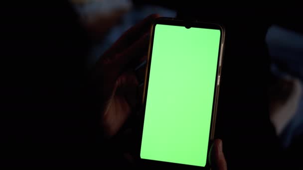 Mâinile femeii în întuneric deține și examinează smartphone-ul cu ecran tactil verde . — Videoclip de stoc
