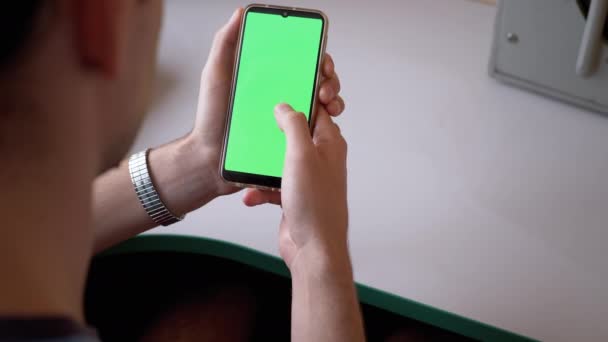 Homem mantém um smartphone com tela verde e tela de pergaminhos com dedos. — Vídeo de Stock