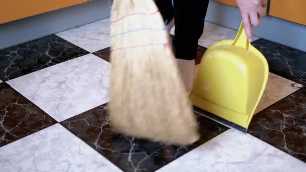 Lustige Frau tanzt und fegt Boden in Socken in Küche mit Besen und Schaufel — Stockvideo
