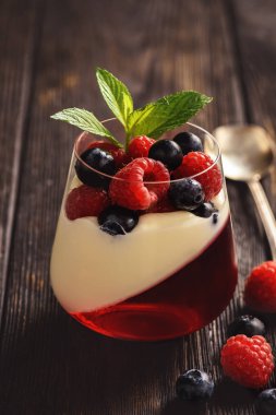 Pannacotta berry jelly ve meyveleri koyu arka plan üzerinde.