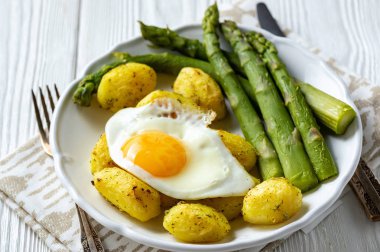 Kızarmış yumurta ve kavrulmuş patates ile ızgara kuşkonmaz.