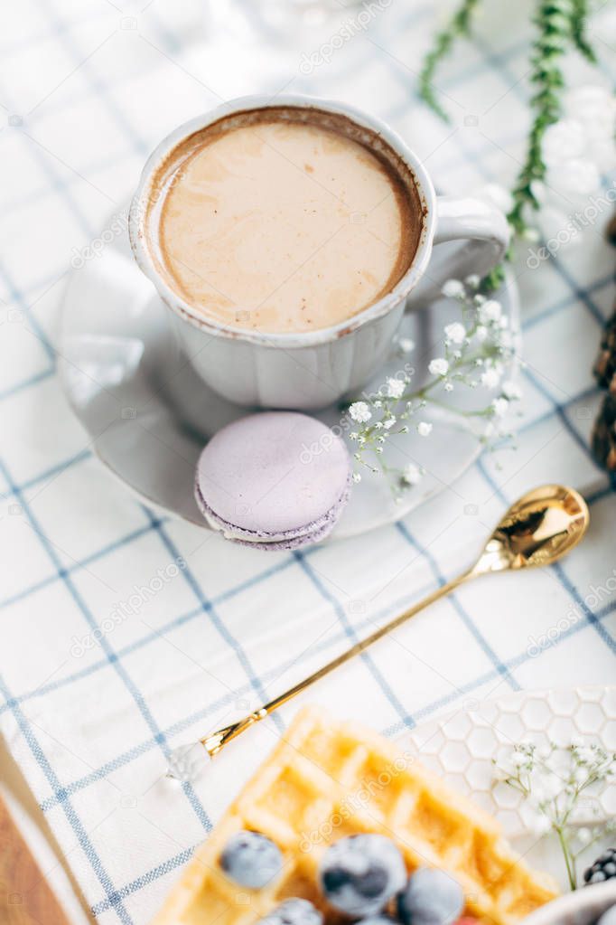 Cup of coffee with macaroon and flowers