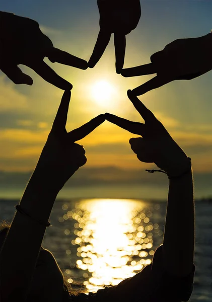 Many hands connecting to star shape at sunset, Teamwork Concept