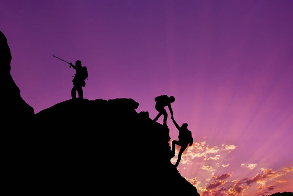 Туристы карабкаются на скалы, горы на закате, один из них протягивает руку и помогает в восхождении.Командная работа, помощь, успех, победитель и лидерство концепции
 .