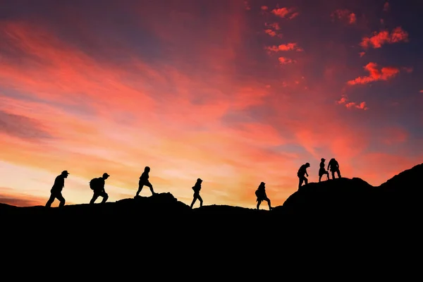 Oito amigos caminham no caminho da montanha ao pôr do sol Imagens De Bancos De Imagens