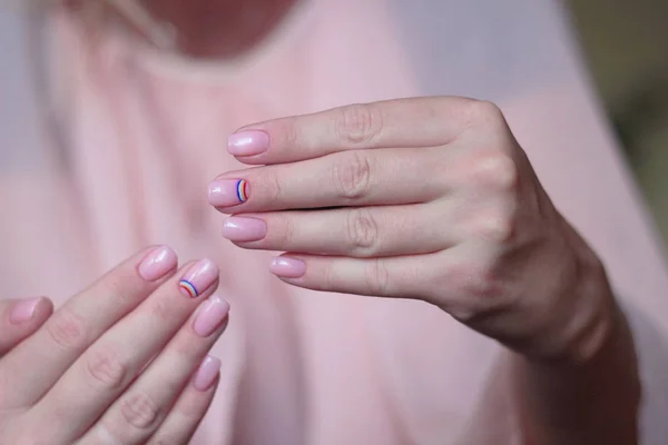 rainbow manicure on a light pink background