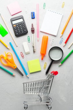 Alışveriş sepeti beyaz sıva arka plan üzerinde oyuncak yakın yalan çeşitli okul malzemeleri.