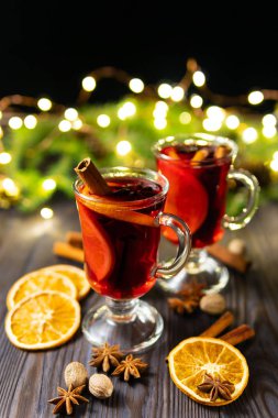 Cam bardak ile baharat ve koyu arka plan üzerinde ahşap masa üzerinde turuncu adet sıcak mulled şarap
