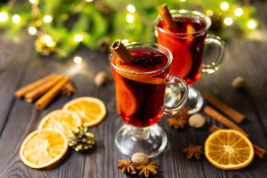 Cam bardak ile baharat ve koyu arka plan üzerinde ahşap masa üzerinde turuncu adet sıcak mulled şarap