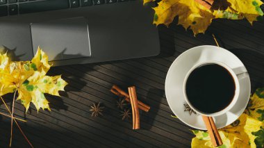 Ahşap masa üstünde laptop düzenleme ile fincan kahve ve Aromatik baharatlar ile düşmüş akçaağaç yaprakları