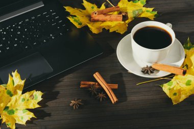 Ahşap masa üstünde laptop düzenleme ile fincan kahve ve Aromatik baharatlar ile düşmüş akçaağaç yaprakları