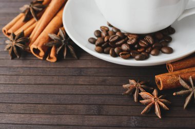 Yakın çekim shot tarçın ve anason ile ahşap masa üzerinde kavrulmuş kahve çekirdekleri ile beyaz Kupası