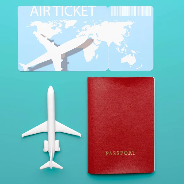 Close-up shot of small toy airplane lying near passport and plane ticket on bright turquoise background