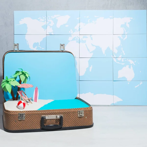 Creative arrangement of toy beach layout inside of suitcase on background of world map