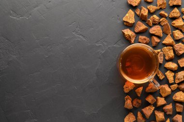 Chaga mantarı siyah arka planda cam bardakta içilir. Sağlıklı içecek..