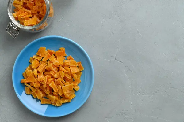 Tranches de citrouille séchées dans un bol sur un fond de pierre grise. Citrouille confite. — Photo