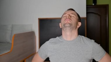 Genç bir adam evde egzersiz yaparken esneme hareketleri yapıyor..