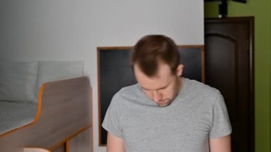 Genç bir adam evde egzersiz yaparken esneme hareketleri yapıyor..