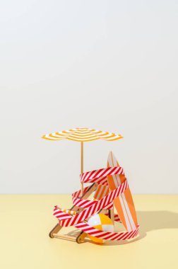 Güverte sandalyesi, şemsiye, sörf tahtası ve top plajda koruyucu bir sinyal bandıyla sarılmış..