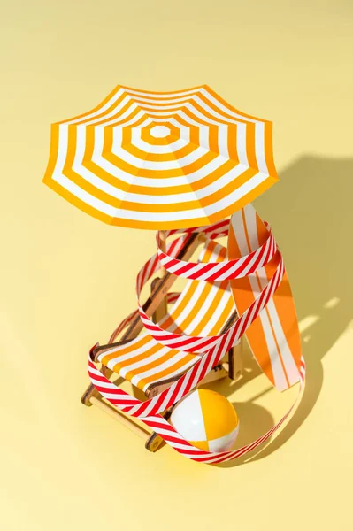 Uma cadeira de praia, um guarda-chuva, uma prancha de surf e uma bola são enrolados com uma fita protetora na praia. . — Fotografia de Stock