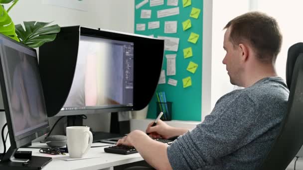 Jovem fotógrafo masculino processa fotos em um computador em casa . — Vídeo de Stock