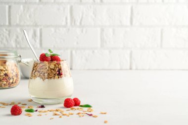 Parfümlü yoğurt, granola ve ahududu bir bardakta, hafif arka plan, kopyalama alanı.