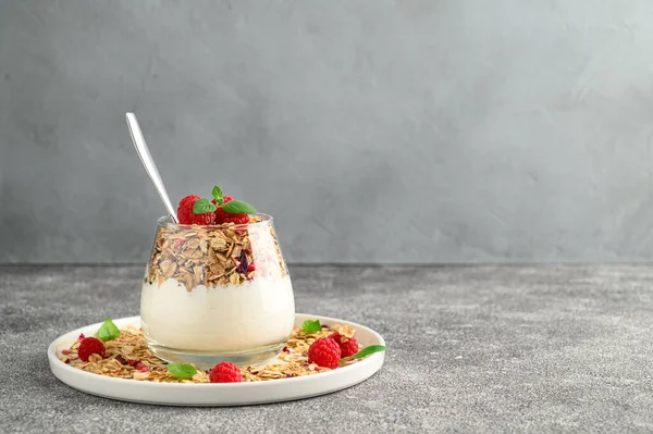 Parfait yogurt with granola and raspberries in a glass. — Stock Photo, Image