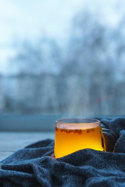 Deniz dikenli üzümlü, sıcak ve sağlıklı bir içecek. Bir sonbahar günü pencere eşiğinde böğürtlen çayı ile cam bardak..