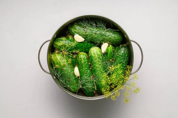 Hälsosam fermenterad mat. Gröna gurkor med vitlök, dill och peppar i en kastrull på en mörk träskiva. — Stockfoto