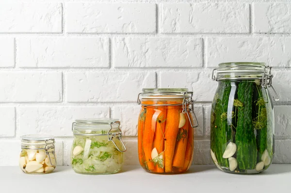 Здоровое веганское питание. Домашние ферментированные овощи огурцы, морковь, капуста и чеснок в стеклянной банке. — стоковое фото