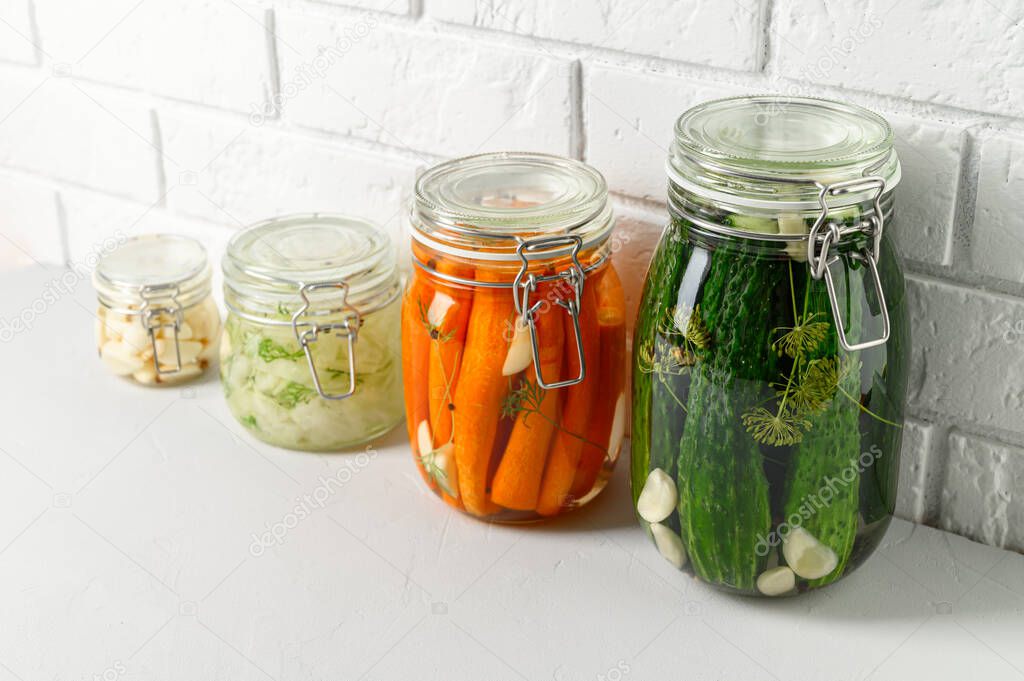 Healthy vegan food. Homemade fermented vegetables cucumbers, carrots, cabbage and garlic in glass jars.