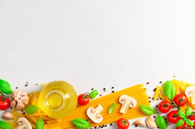 Spagetti ve mantarlı İtalyan makarnası pişirmek için kullanılan malzemeler açık gri arka planda..