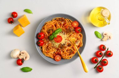 Geleneksel İtalyan mutfağı. Spagetti, domates sosu, vişneli domates, mantar ve açık gri arka planda fesleğen..
