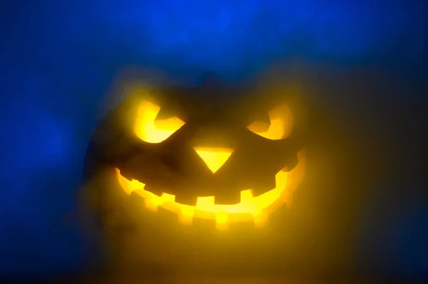 Gruselig leuchtendes Gesicht von Halloween-Kürbis in blauem Rauch. — Stockfoto