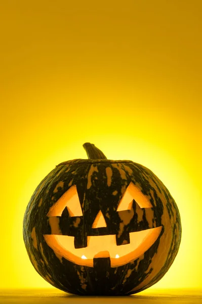 Fijne Halloween. Grappig gloeiende pompoen Jack-o-lantaarn op een gele achtergrond. — Stockfoto