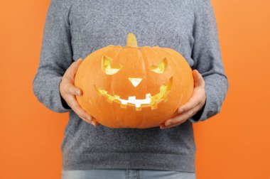 Tanınmayan bir adam önünde oyulmuş bir Cadılar Bayramı kabağı tutuyor..