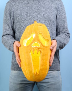 Tanınmayan bir adam önünde oyulmuş bir Cadılar Bayramı kabağı tutuyor..