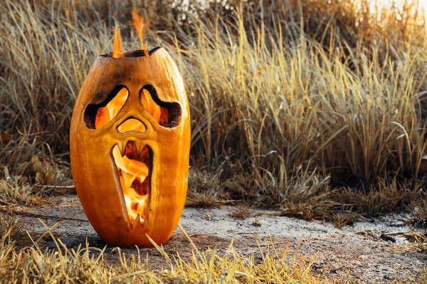 Tema de horror de Halloween. Calabaza de Halloween se quema en el suelo. — Foto de Stock