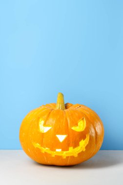 Pastel mavi arka planda parlayan Cadılar Bayramı kabağı.