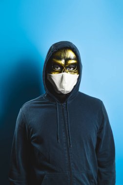 Era Covid. Yeni normal konsept. Kafatası maskeli bir adam portresi ve mavi arka planda koruyucu bir tıbbi maske. Cadılar Bayramı partisi kostümü.