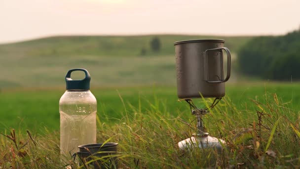 Queimador de gás de acampamento ao ar livre em um fundo de pôr do sol. Cozinhar alimentos durante a caminhada — Vídeo de Stock