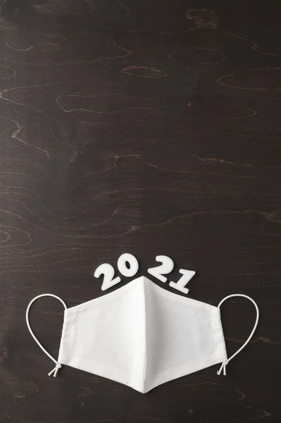 Minimal new year concept. Decorated reusable face mask and the number 2021 on a dark brown background. New normal. — Stock Photo, Image