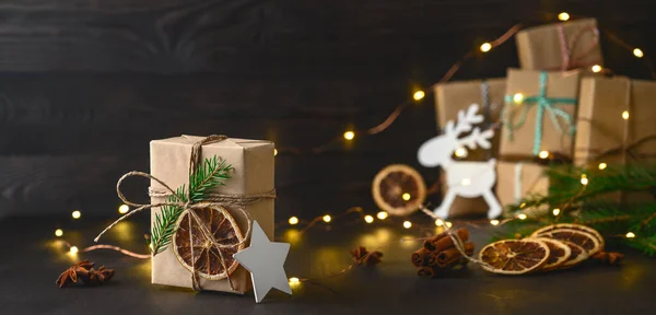 Christmas zero waste concept. Eco friendly packaging gifts in kraft paper on a dark wooden table.