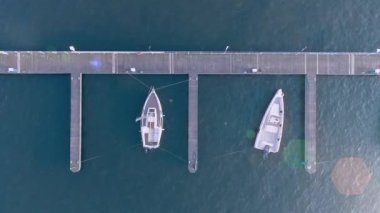 Liman rıhtımındaki yelkenli ve motorlu tekneye hava görüntüsü