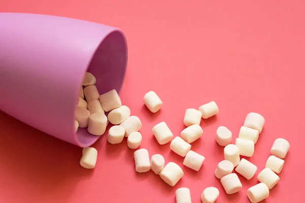 White marshmallow poured from a purple cup on a pink background — Stock Photo, Image