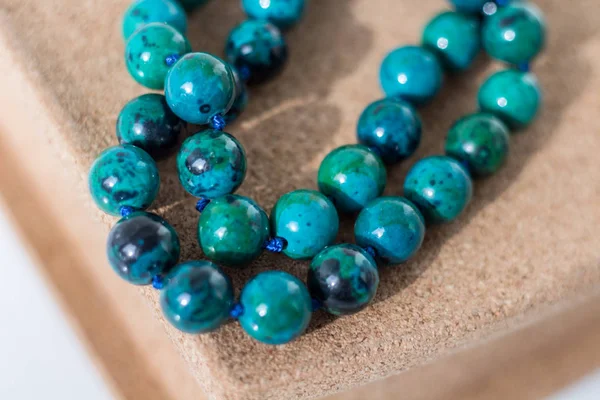 Beads from turquoise lie on a box of cork tree