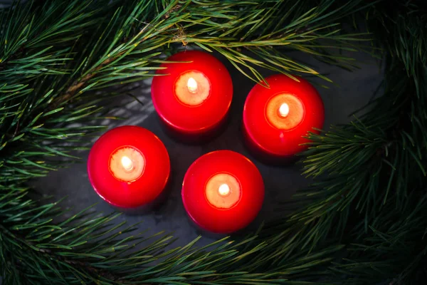 Yeşil çam dalları tarafından çevrili dört kırmızı ışıklı Noel mumlar — Stok fotoğraf