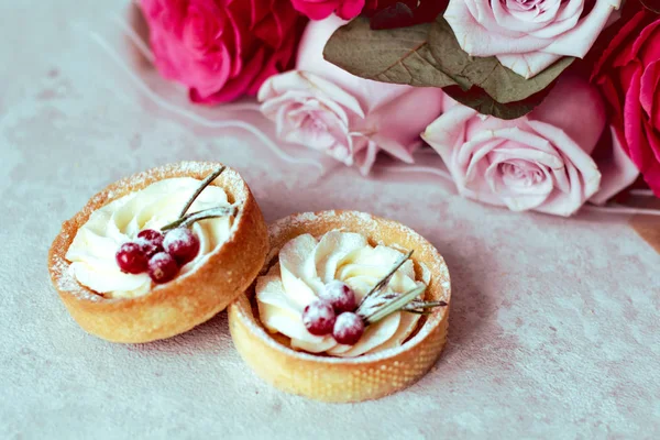 Nabídka Romantické dárky: sladké dorty se smetanou a bobule a kytice z růžových růží na světlém pozadí — Stock fotografie