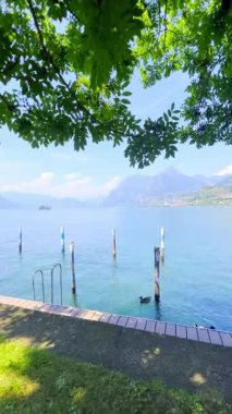 İtalya 'daki mavi gökyüzünü yansıtan sakin bir Iseo gölünün olduğu çarpıcı bir manzara. Yeşillik tarafından çerçevelenmiş görkemli dağlar uzaklardan yükselir. Huzurlu ve görkemli bir manzara yaratır..